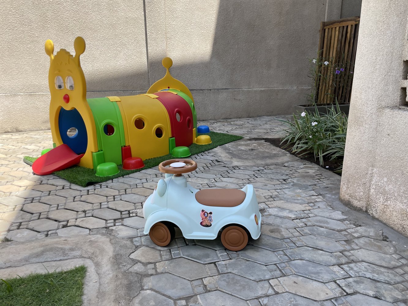 Espace extérieur de jeu de la crèche avec tunnel coloré et petite voiture
