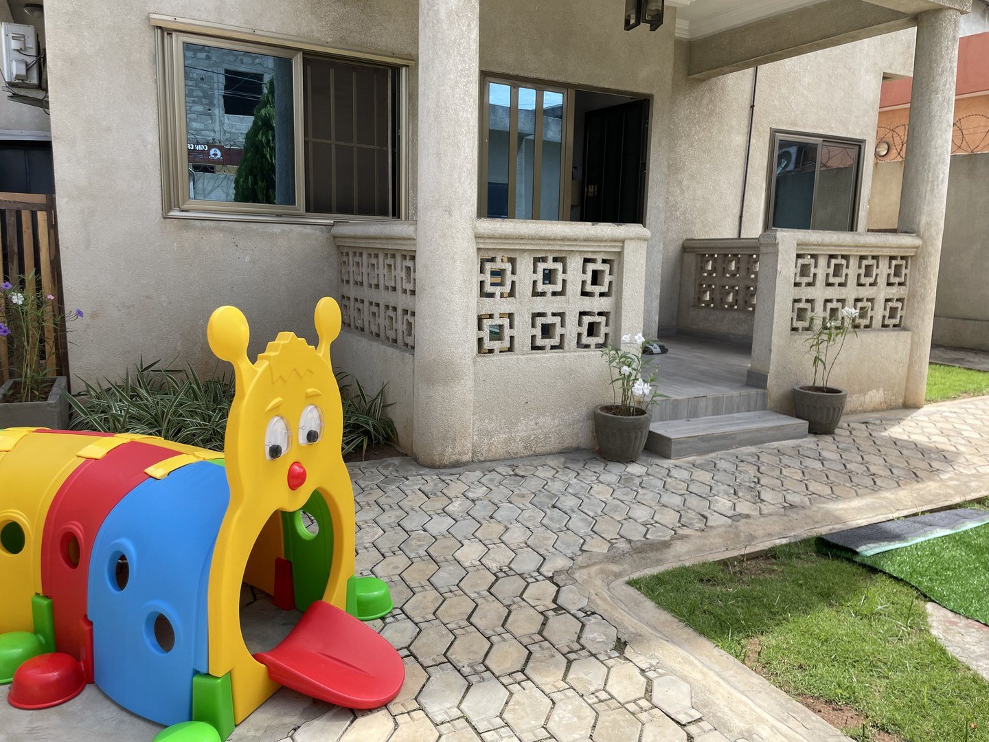 Cour extérieure de la Crèche La Girafe Pablo avec tunnel de jeu coloré